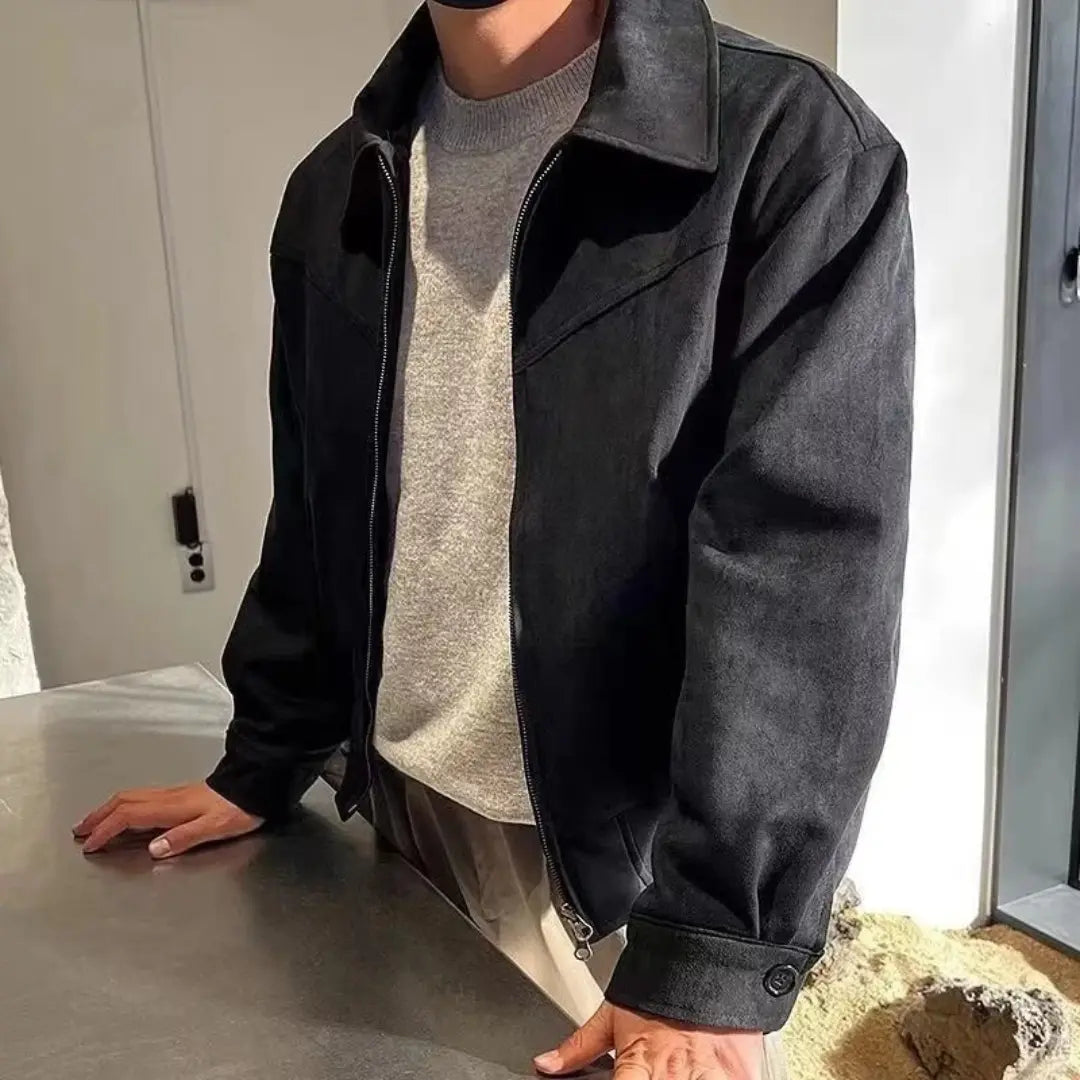 Person wearing a black jacket over a gray shirt indoors.