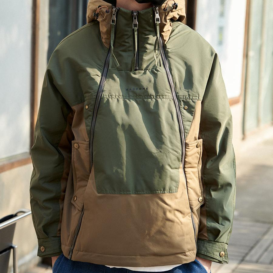 Green and brown jacket with a hood worn by a person, blurred background