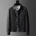 A men's dark gray suede or faux-suede jacket displayed on a black hanger over a white t-shirt, set against a dark gray gradient background.