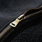 Close-up of a brass zipper on a black textured fabric background