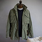 Green jacket on a mannequin against a plain background