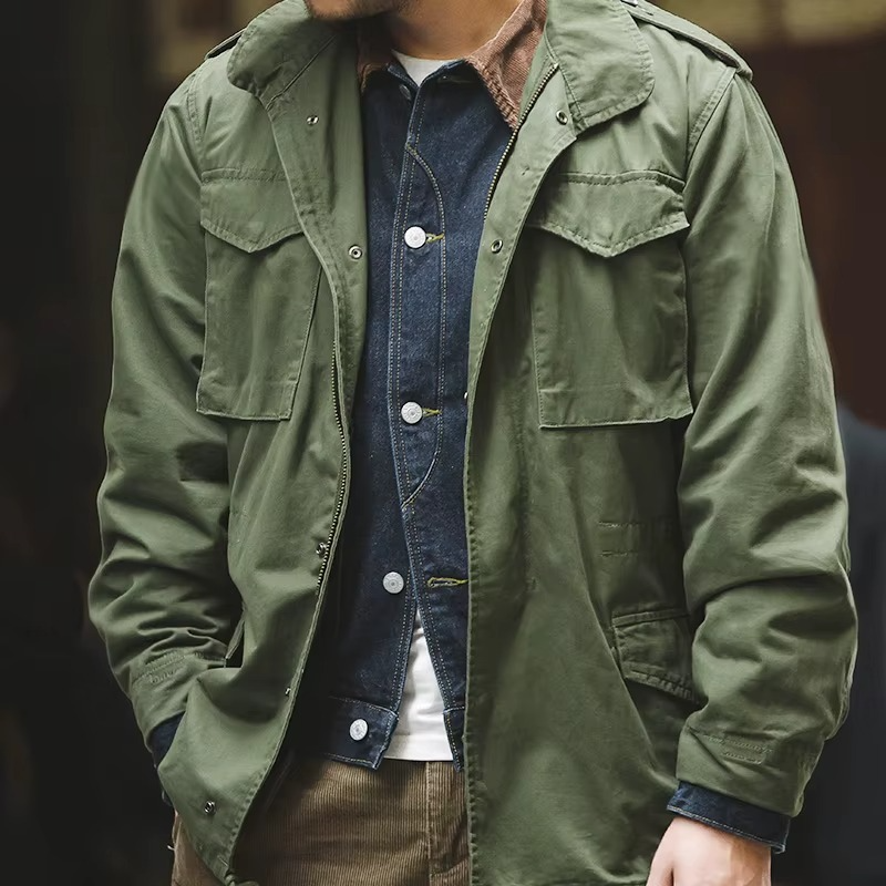 Person wearing a green jacket over a denim shirt with a blurred background