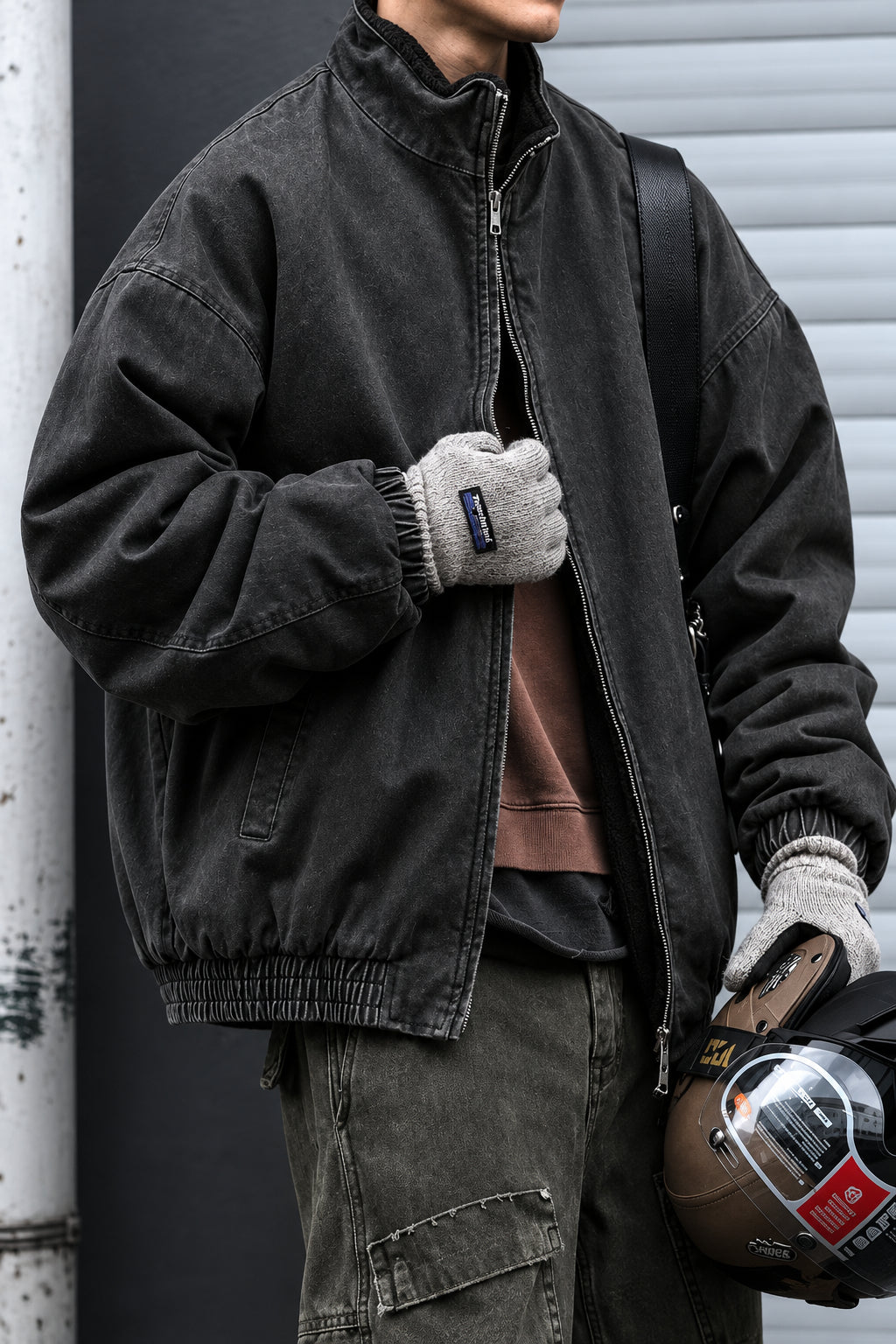 Person wearing a dark jacket and holding a bag with a visible brand logo.