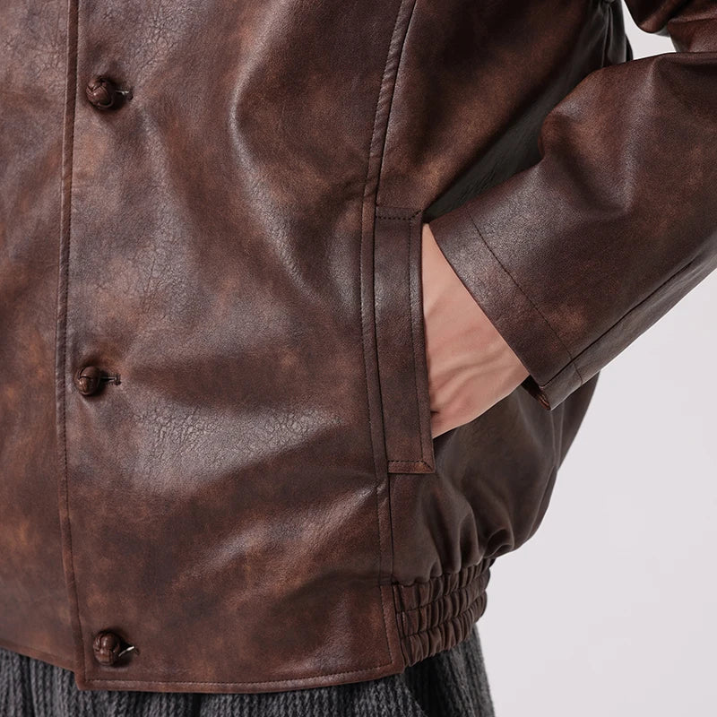 Close-up of a brown leather jacket with buttons on a light gray background