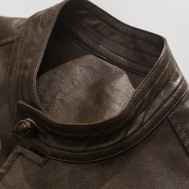 Close-up of a brown leather jacket with a button detail on a light gray background