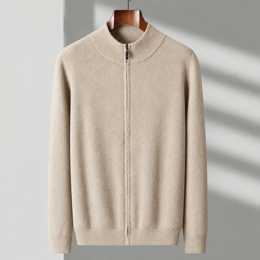 A beige ribbed knit zip-up sweater with a mock neck and long sleeves, hanging on a wooden hanger against a light gray wall with soft diagonal shadows.