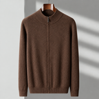 A brown ribbed knit zip-up sweater with a mock neck collar, hanging on a wooden hanger against a light gray wall with soft diagonal shadows.