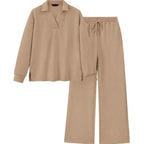 A two-piece lounge set in a warm beige color with a subtle textured herringbone pattern, featuring a long-sleeve polo-style top and matching drawstring pants, displayed on a solid white background.