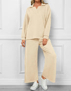 Woman wearing a beige textured outfit with wide-leg pants against a white paneled wall.