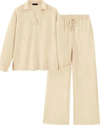 A two-piece loungewear set in a light cream color with a subtle textured pattern, featuring a long-sleeve polo-style top and matching wide-leg pants with an elastic drawstring waist.
