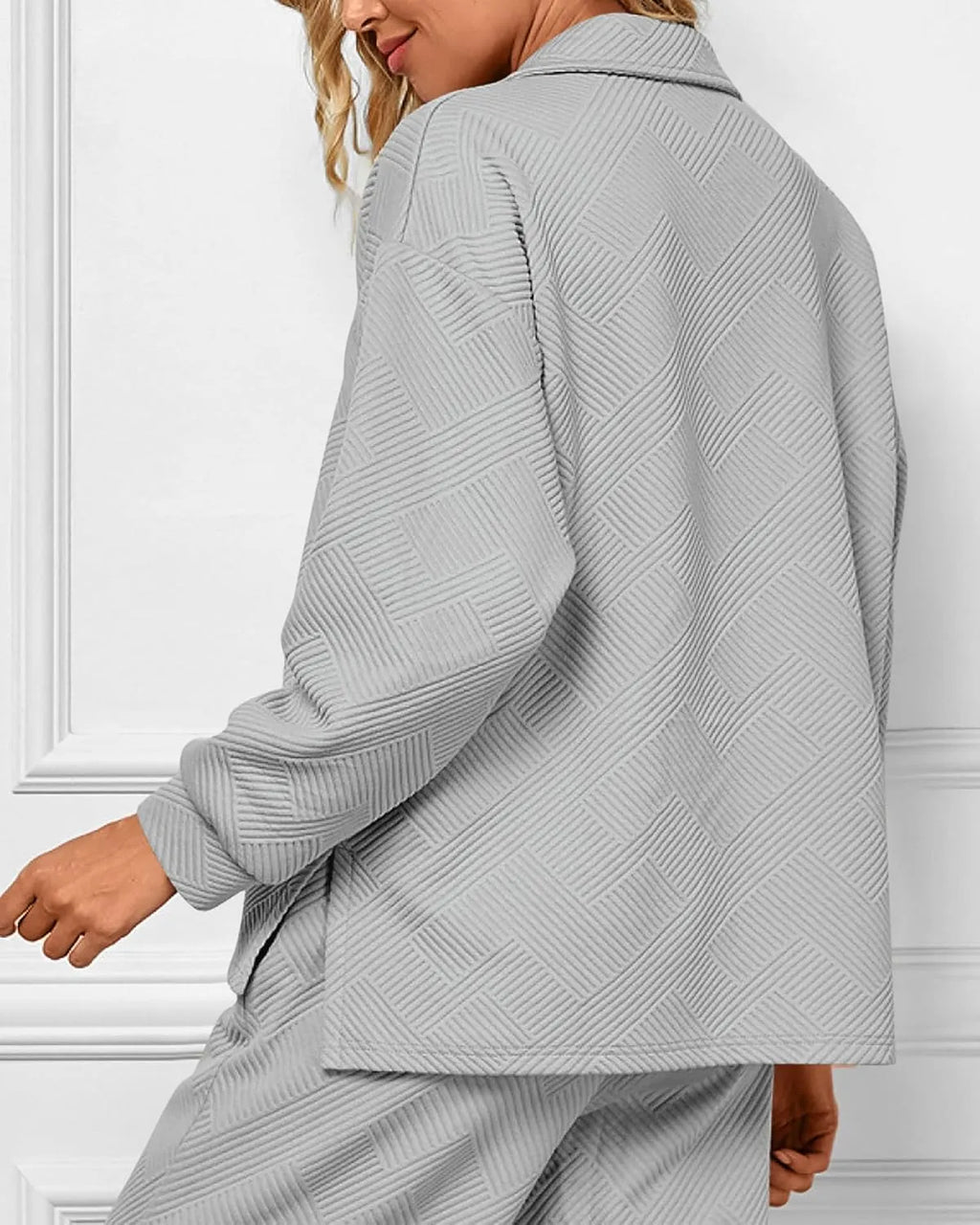 Person wearing a gray textured coat against a white background