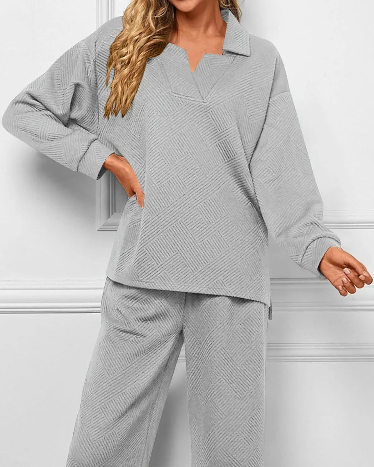 Woman wearing a gray textured outfit against a white wall