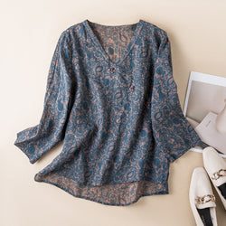 Blue patterned blouse on a beige surface with a magazine and shoes in the background