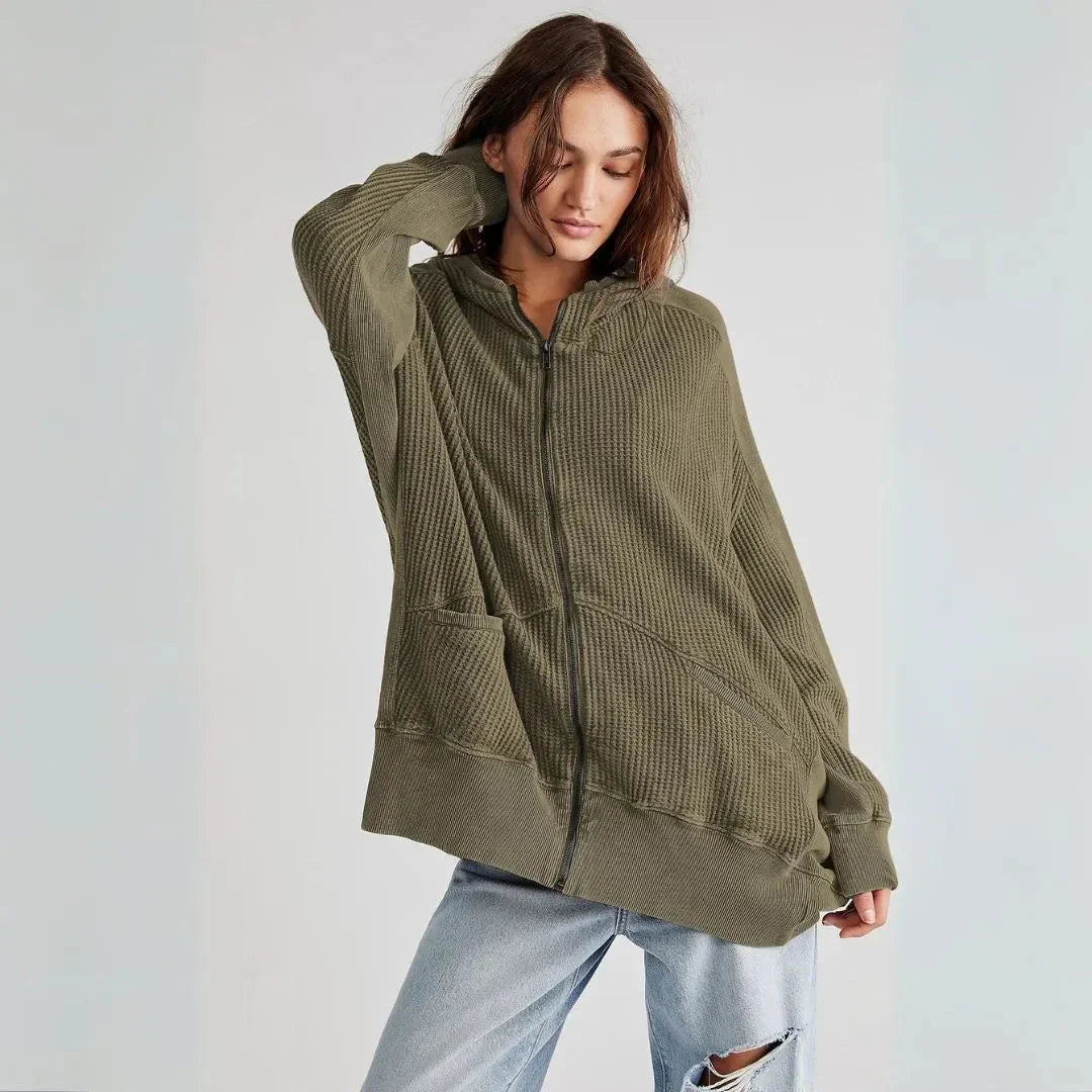 Woman wearing a green zip-up hoodie against a light gray background