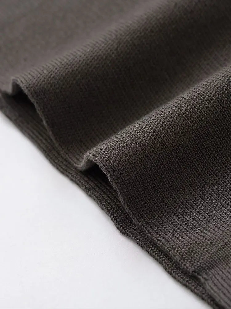 Close-up of a dark charcoal gray ribbed knit fabric draped diagonally over a white surface, showing the detailed knit texture.