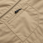 Close-up of a beige jacket or vest showing a zippered pocket with a small black fabric pull tab.