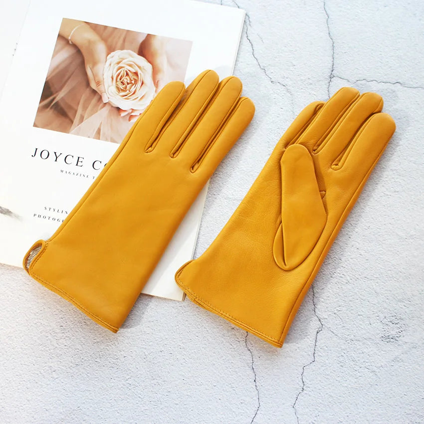 Pair of mustard yellow gloves on a textured surface with a magazine underneath.