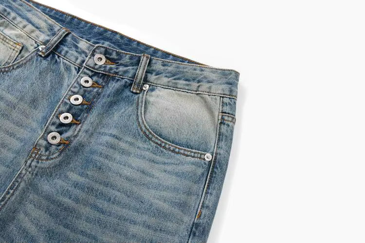 Close-up of a pair of blue denim jeans showing the waistband, button fly, belt loops, and front pocket on a white background.