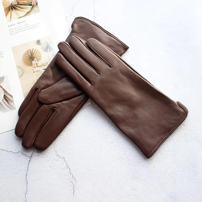 Pair of brown leather gloves on a textured white surface