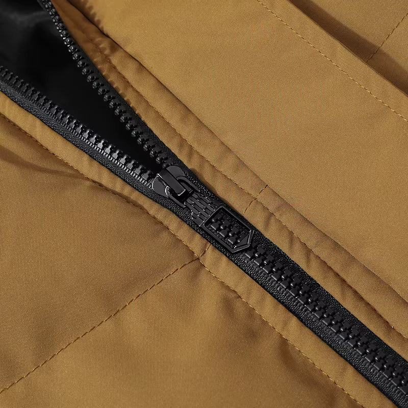 Close-up of a tan or camel-colored jacket with a black zipper running diagonally across the frame.