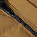Close-up of a tan or camel-colored jacket with a black zipper running diagonally across the frame.