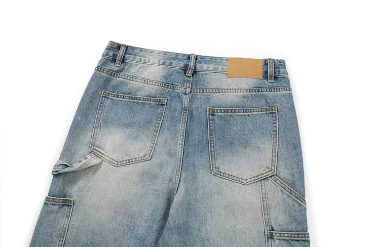 Back view of light blue denim jeans showing the waistband, belt loops, back pockets, and a small tan leather patch on a white background.