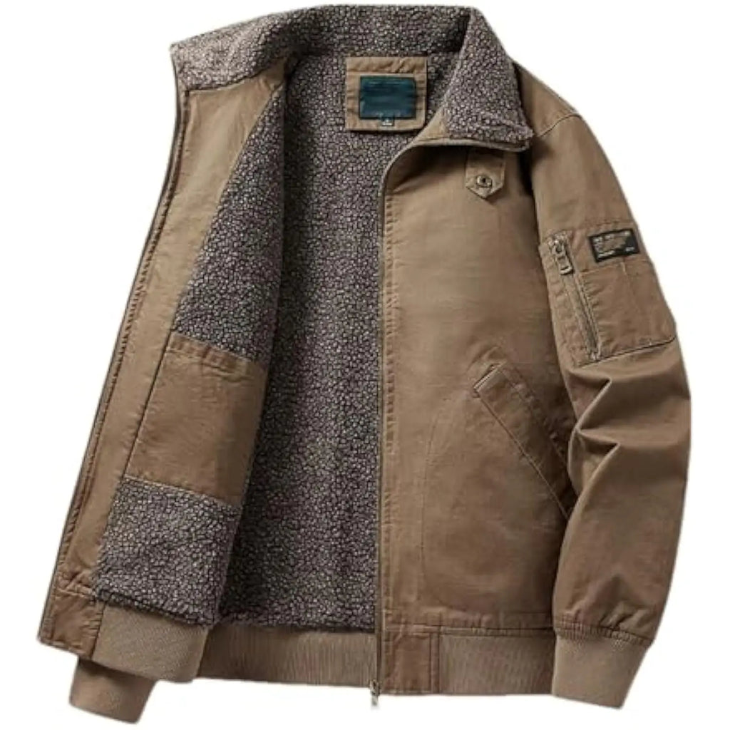A men's tan utility jacket with a thick gray fleece lining, ribbed knit collar, cuffs, and hem, featuring a front zipper, chest pockets, and a zippered sleeve pocket.