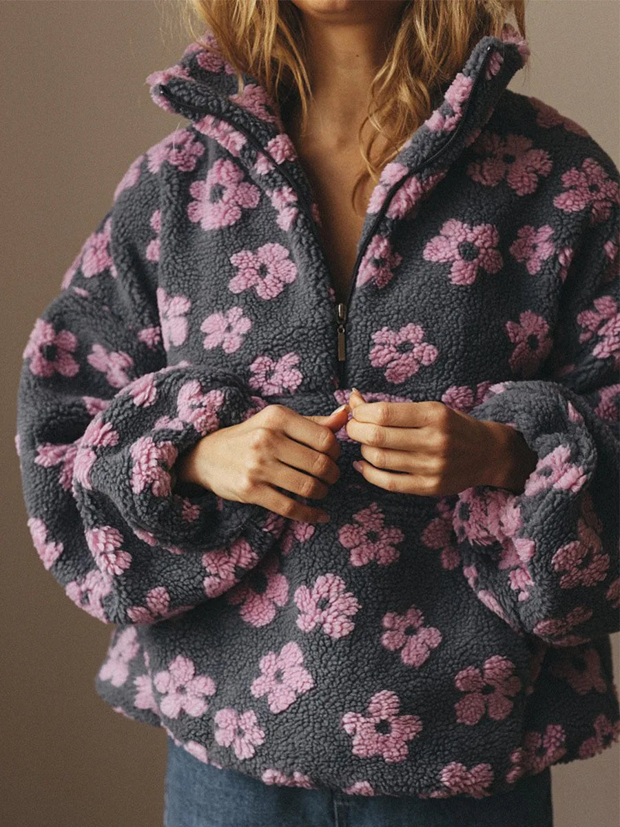 Person wearing a dark gray fleece jacket with pink floral pattern on a plain background