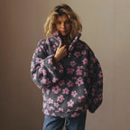 Person wearing a dark gray fleece pullover with pink floral pattern against a plain background