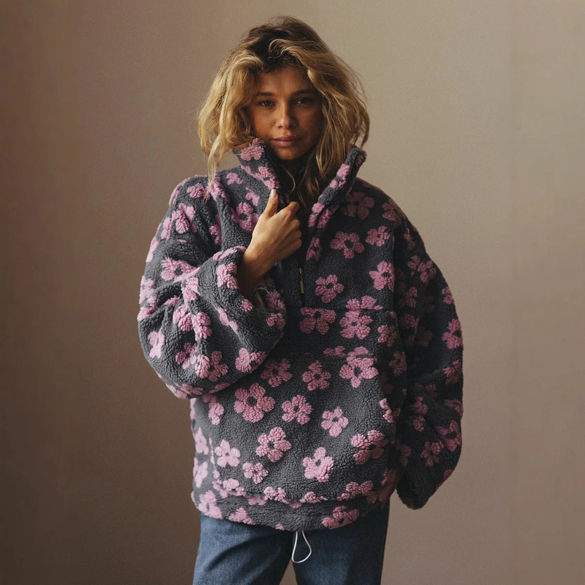 Person wearing a dark gray fleece pullover with pink floral pattern against a plain background