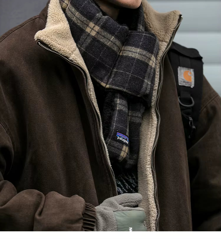 Person wearing a brown jacket with a plaid scarf and gloves, featuring Carhartt branding.