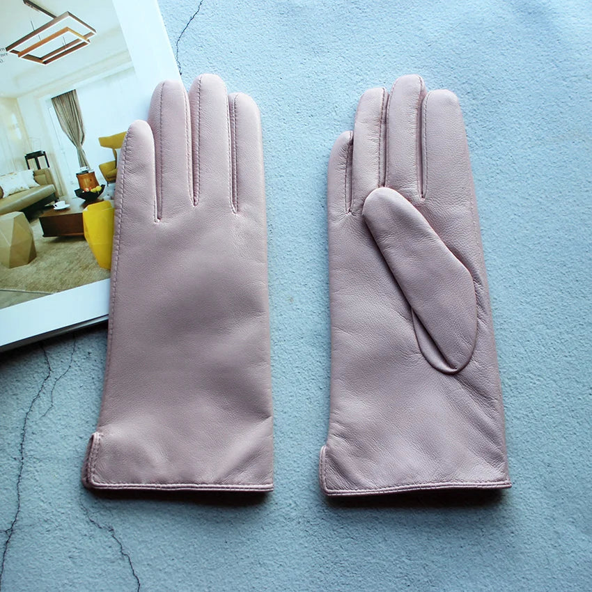Pair of pink gloves on a textured blue surface with a blurred indoor setting in the background.