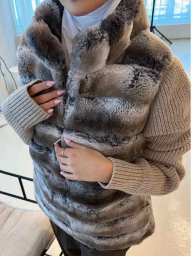 Person wearing a fur vest over a sweater in an indoor setting