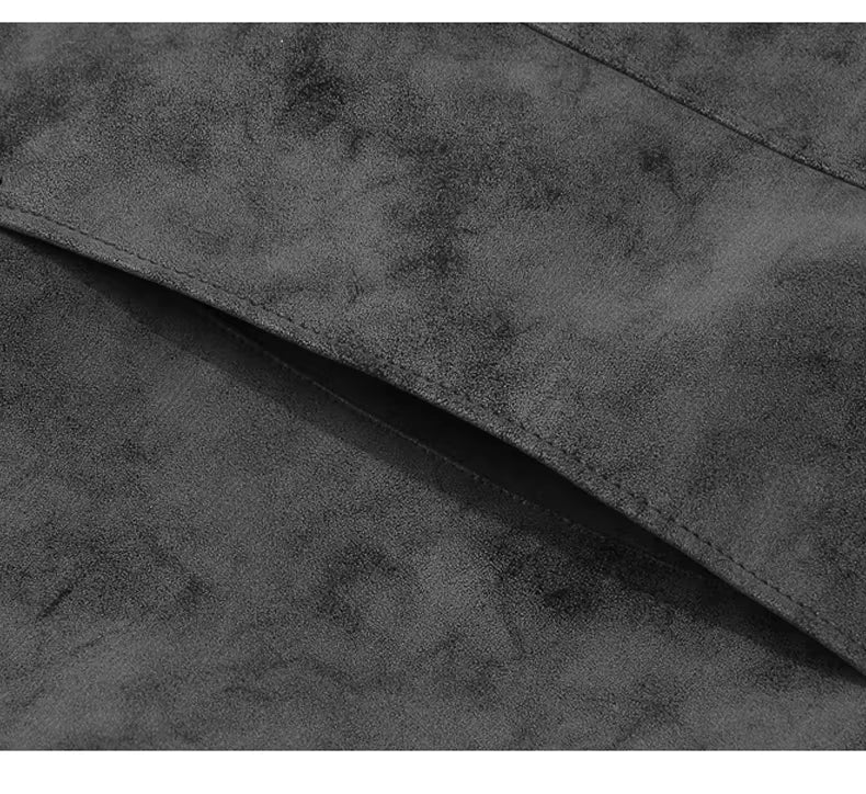 Close-up of a dark gray suede or microfiber fabric texture with a folded corner showing the material's soft, mottled surface.