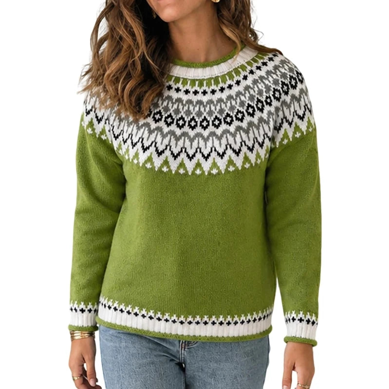 A woman wearing a green knit sweater with a white and gray geometric Fair Isle yoke pattern, paired with blue jeans, against a plain white background.