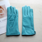 Pair of turquoise gloves on a light surface with a magazine in the background