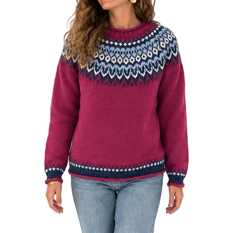 A woman wearing a long-sleeve knit sweater with a magenta body and a navy, blue, and white Fair Isle yoke pattern, paired with light-wash blue jeans against a plain white background.