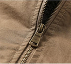 Close-up of a brown fabric jacket with a silver metal zipper and pull tab.