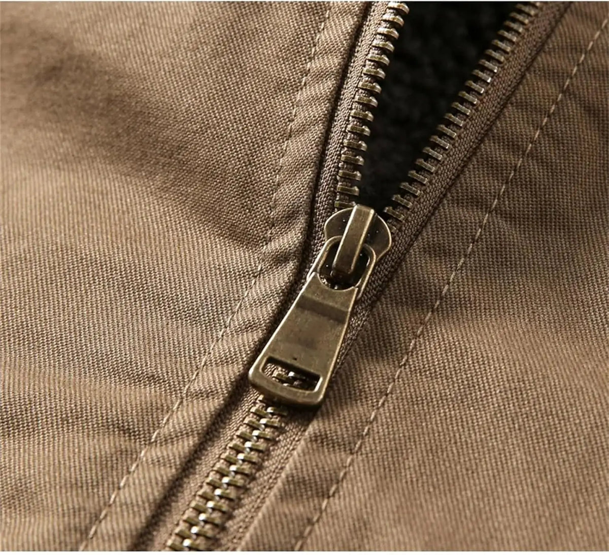Close-up of a brown fabric jacket with a silver metal zipper and pull tab.