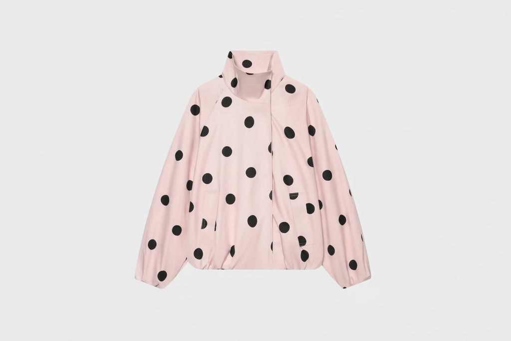 A light pink lightweight jacket with black polka dots, featuring a stand-up collar and front zipper, shown against a plain white background.