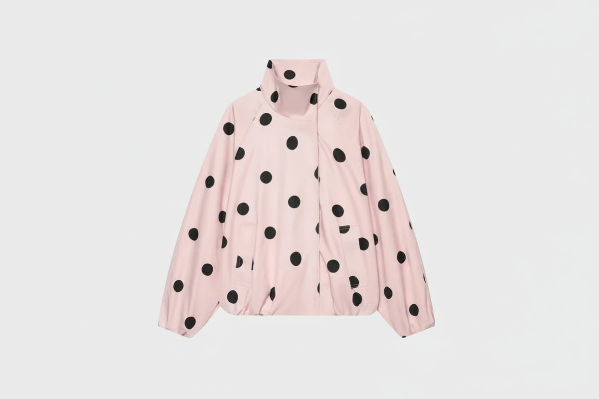 A light pink lightweight jacket with black polka dots, featuring a stand-up collar and front zipper, shown against a plain white background.