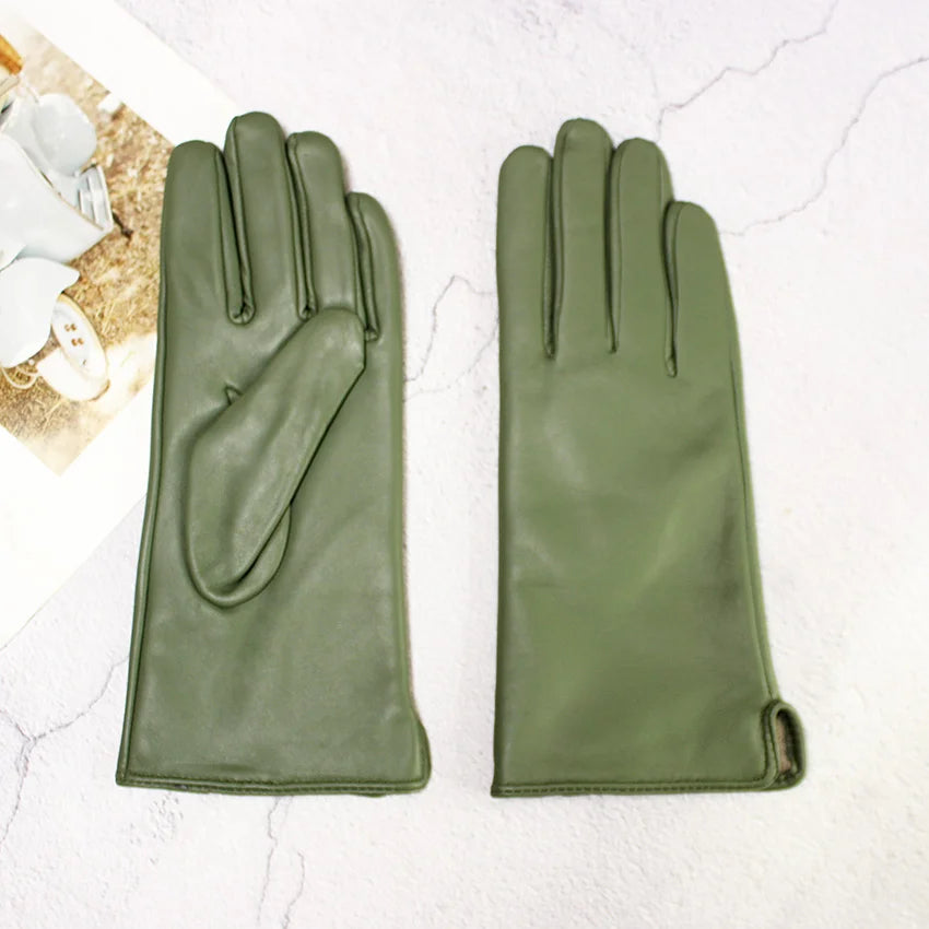 Pair of green leather gloves on a light marble background