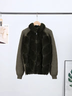 Green sweater with black fur vest over it on a hanger against a white background