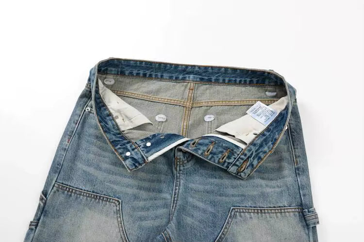 A close-up of folded light-to-medium wash blue denim jeans showing the waistband, button closure, inner lining, and interior tags against a plain white background.