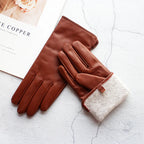 Pair of brown leather gloves with a beige lining on a textured white surface.