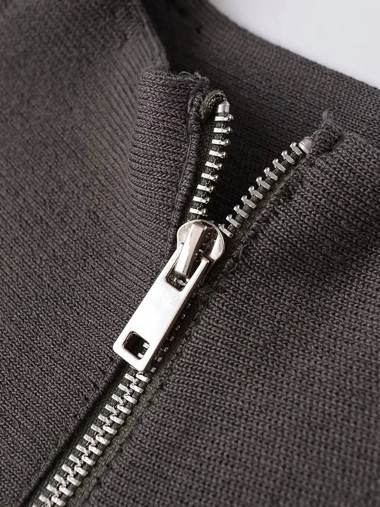 Close-up of a dark charcoal gray ribbed knit garment with a silver metal zipper.