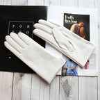 White gloves on top of a magazine with visible text and images.
