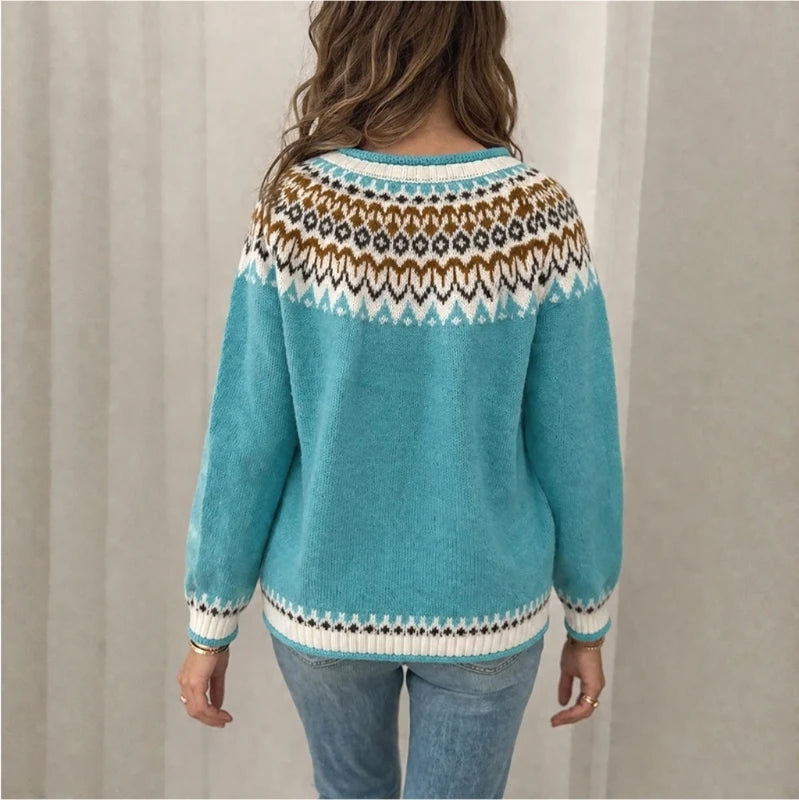 A woman shown from the back wearing a turquoise knit sweater with a brown, white, and black geometric pattern across the shoulders and cuffs, paired with light blue jeans.