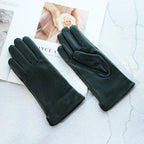 Pair of black leather gloves on a textured surface with a magazine underneath.