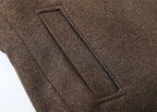 Close-up of a brown wool or felt fabric surface with a rectangular stitched pocket or welt detail.